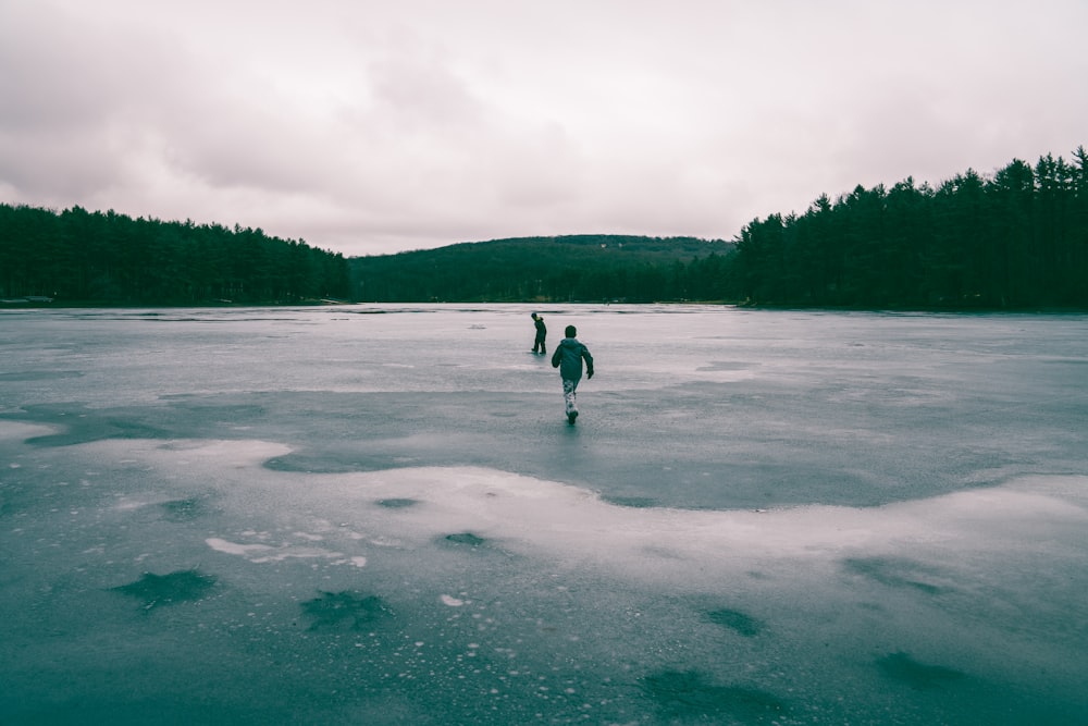 木の近くの凍った水域の真ん中にいる2人