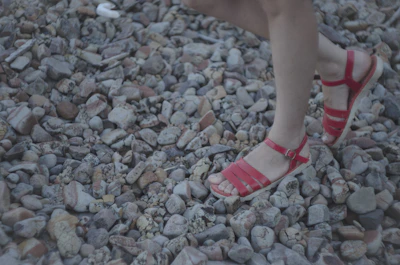 Woman wearing colorful sandals walking on a cobblestone street in a Moroccan medina.