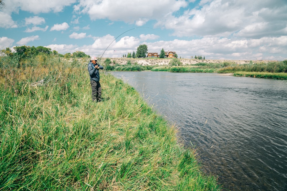 fisherman standing on grass while holding fishing rod