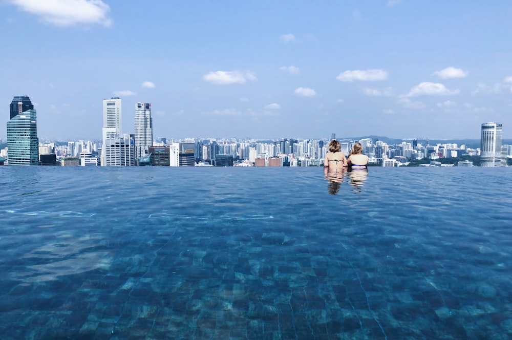 two women's swimming in pool while looking at building