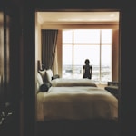 woman standing near window inside bedroom