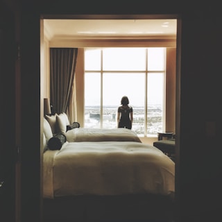 woman standing near window inside bedroom