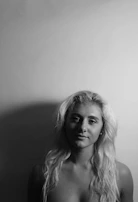 Artistic portrait of a student styling hair with sleek, glossy waves under soft lighting.