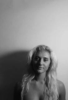 Artistic portrait of a student styling hair with sleek, glossy waves under soft lighting.