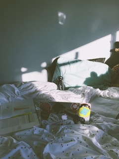 A cozy bedroom corner decorated with fairy lights, books, and a laptop open to a blog page.