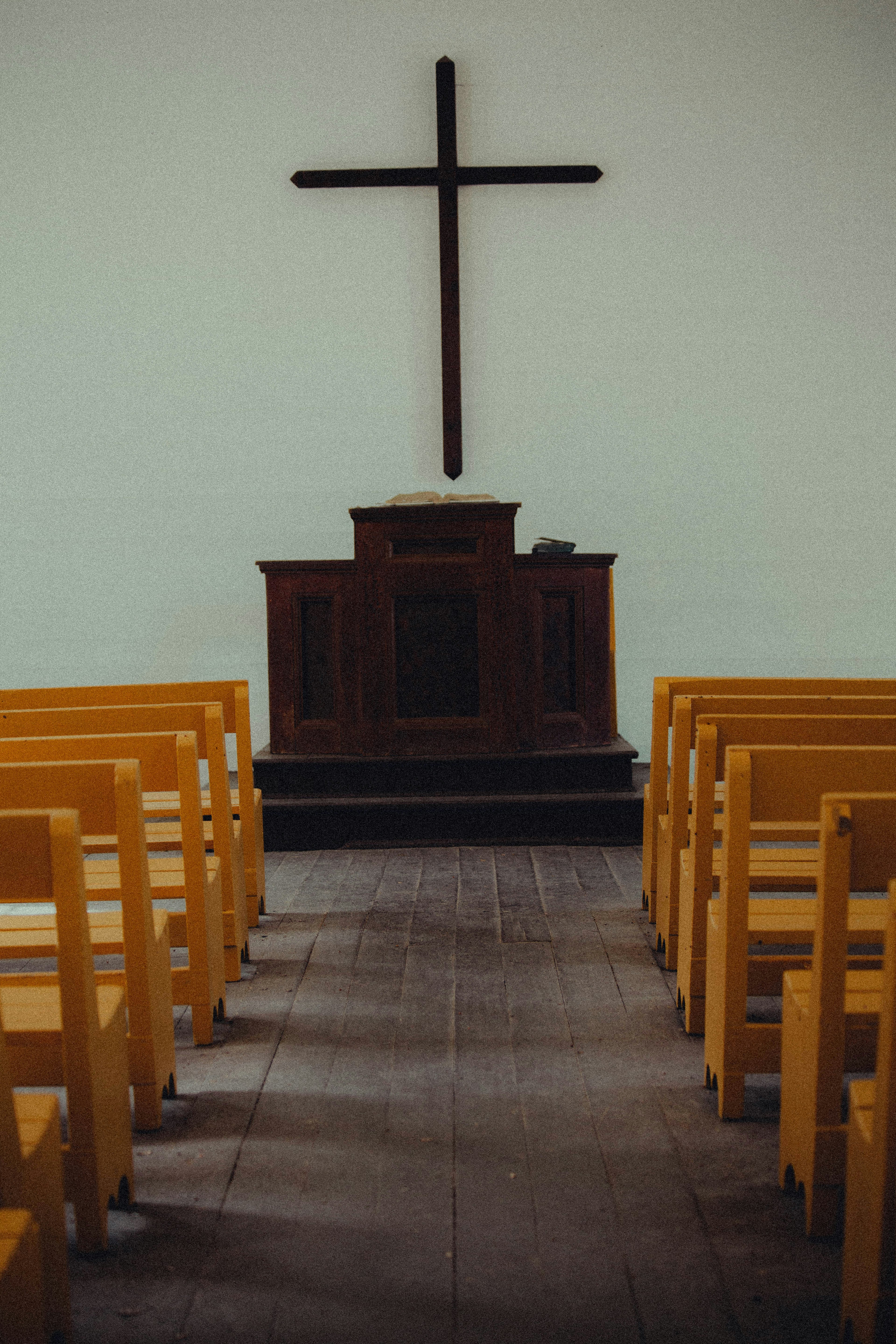 A simple church interior with wooden pews and a plain cross