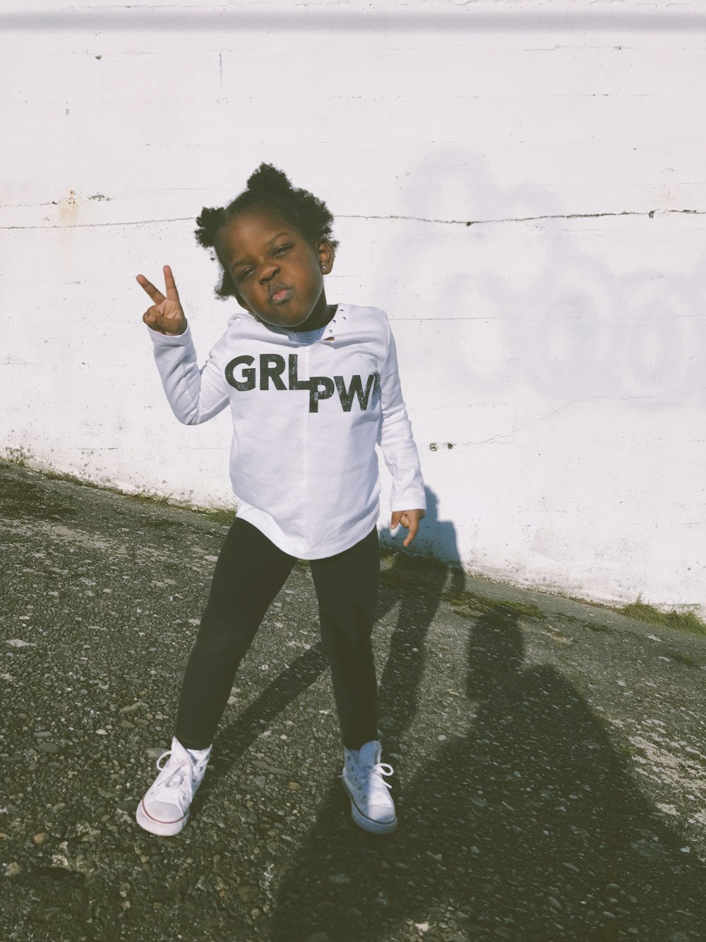 girl wearing white and black sweater doing peace hand sign