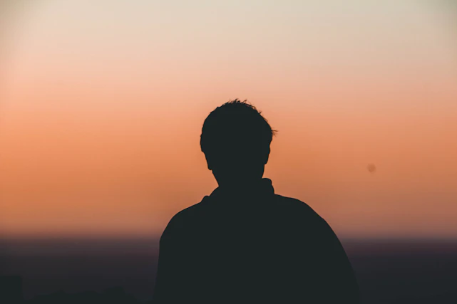 Silhouette of a confident man standing tall with a subtle dark green gradient background symbolizing strength and vitality