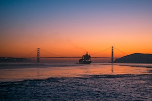A large oil tanker ship navigating through calm ocean waters at sunset.