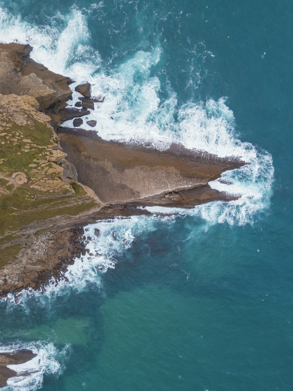 top angle photo of crashing waves on brown rock formation