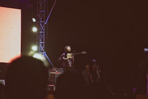 A lively guitarist performing on stage with colorful lights in the background