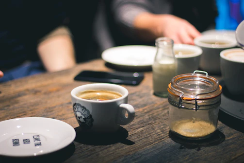 A cozy home setting with a phone and a cup of coffee on a wooden table