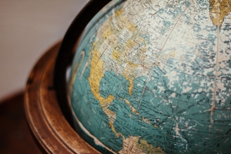 A close-up of a classic globe depicting parts of North and Central America with visible geographical names. The globe rests within a wooden frame.