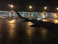 Nighttime shot of a Gatwick Group Transfers coach illuminated by airport lights, ready for a late flight pickup.