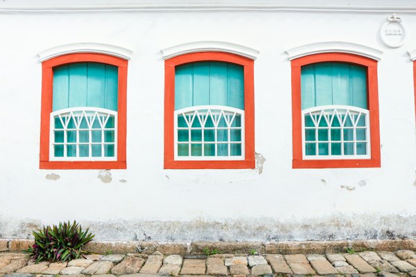 Shuttered windows framed in colour on a whitewashed house — Paraty, Brazil