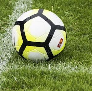 white and green soccer ball on green grass