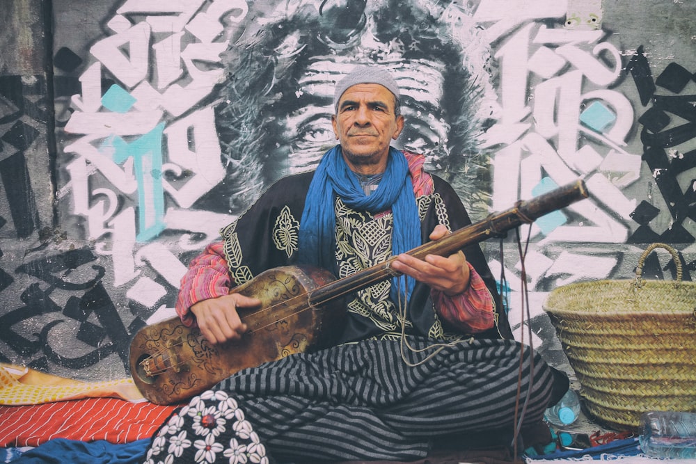 man playing string instrument beside brown basket