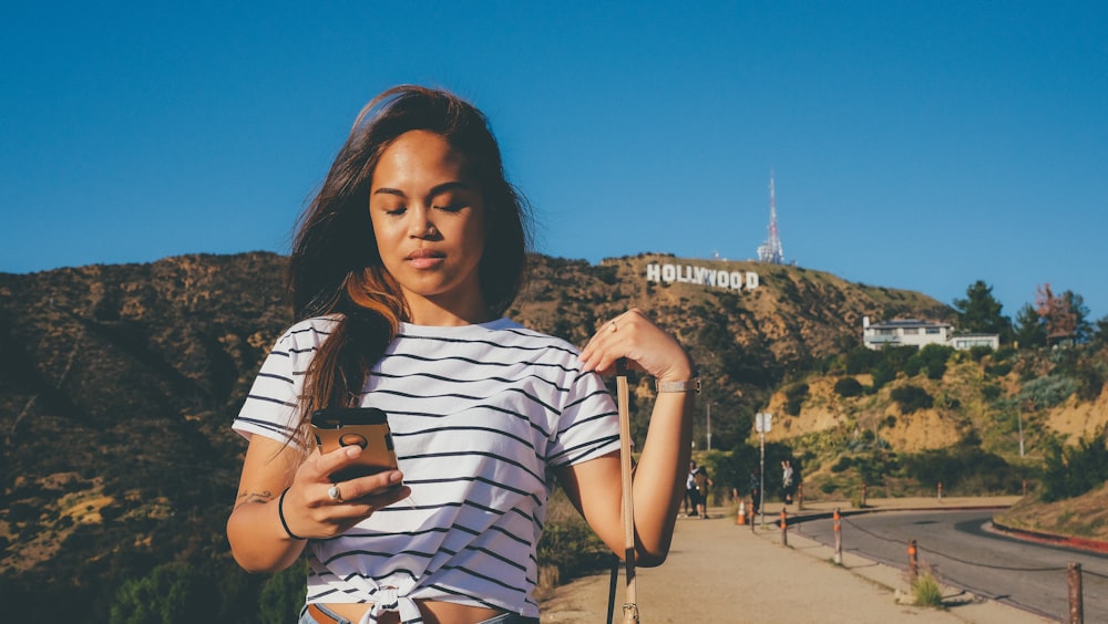 woman in black and white striped T-shirt standing behind Hollywood signage