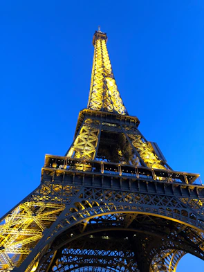 The iconic Eiffel Tower illuminated at night with a clear sky background.
