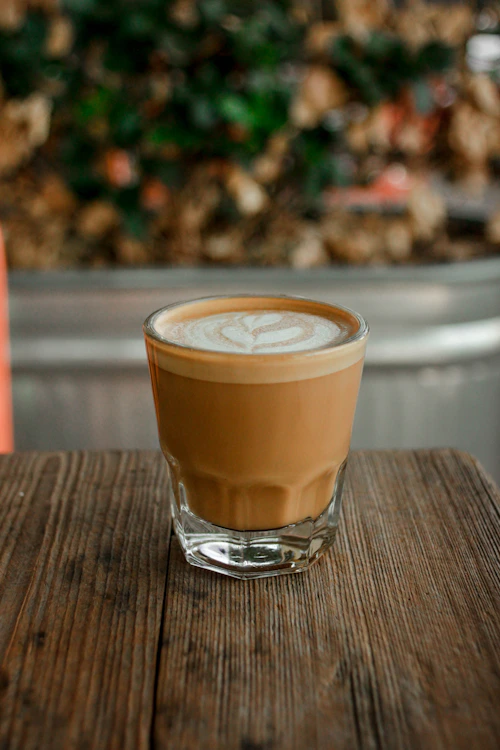 Cortado coffee in a small glass on a wooden table