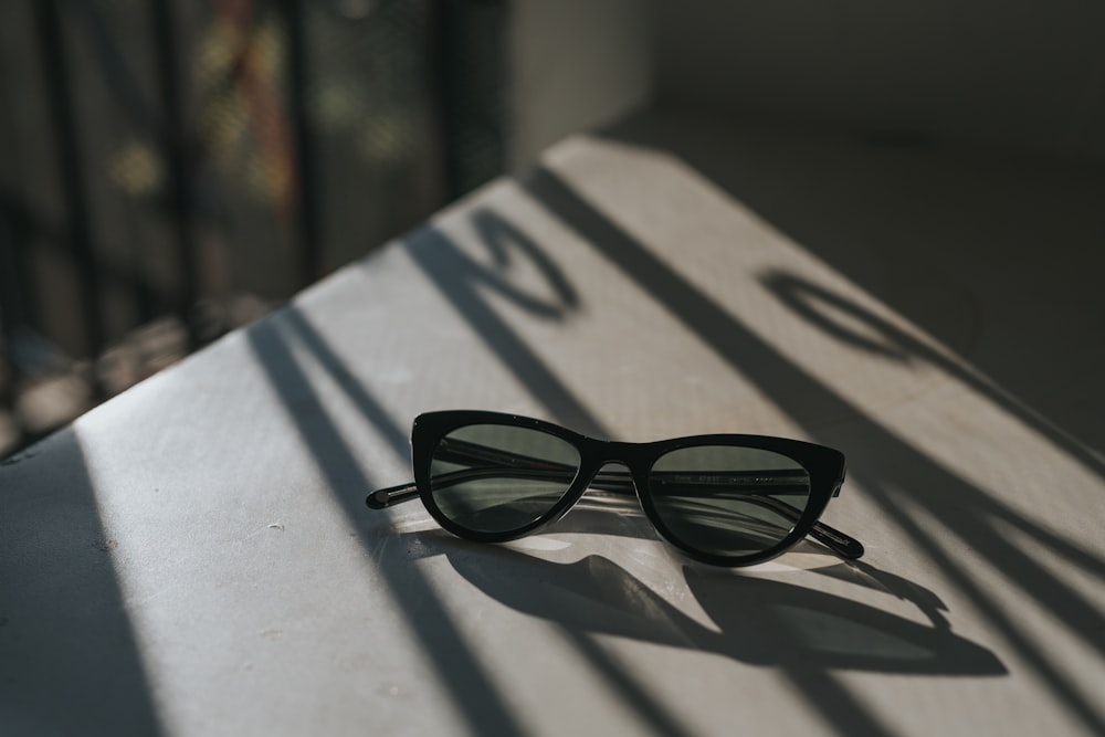 occhiali da sole con montatura nera su superficie bianca