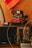 A vintage setup featuring a retro Polaroid camera, an old-fashioned radio with a tuning dial, and a reserved sign. A bicycle wheel and a crocheted orange fabric are partially visible, adding to the nostalgic ambiance.