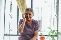 Smiling elderly woman wearing Oricle hearing aids while chatting with family outdoors.