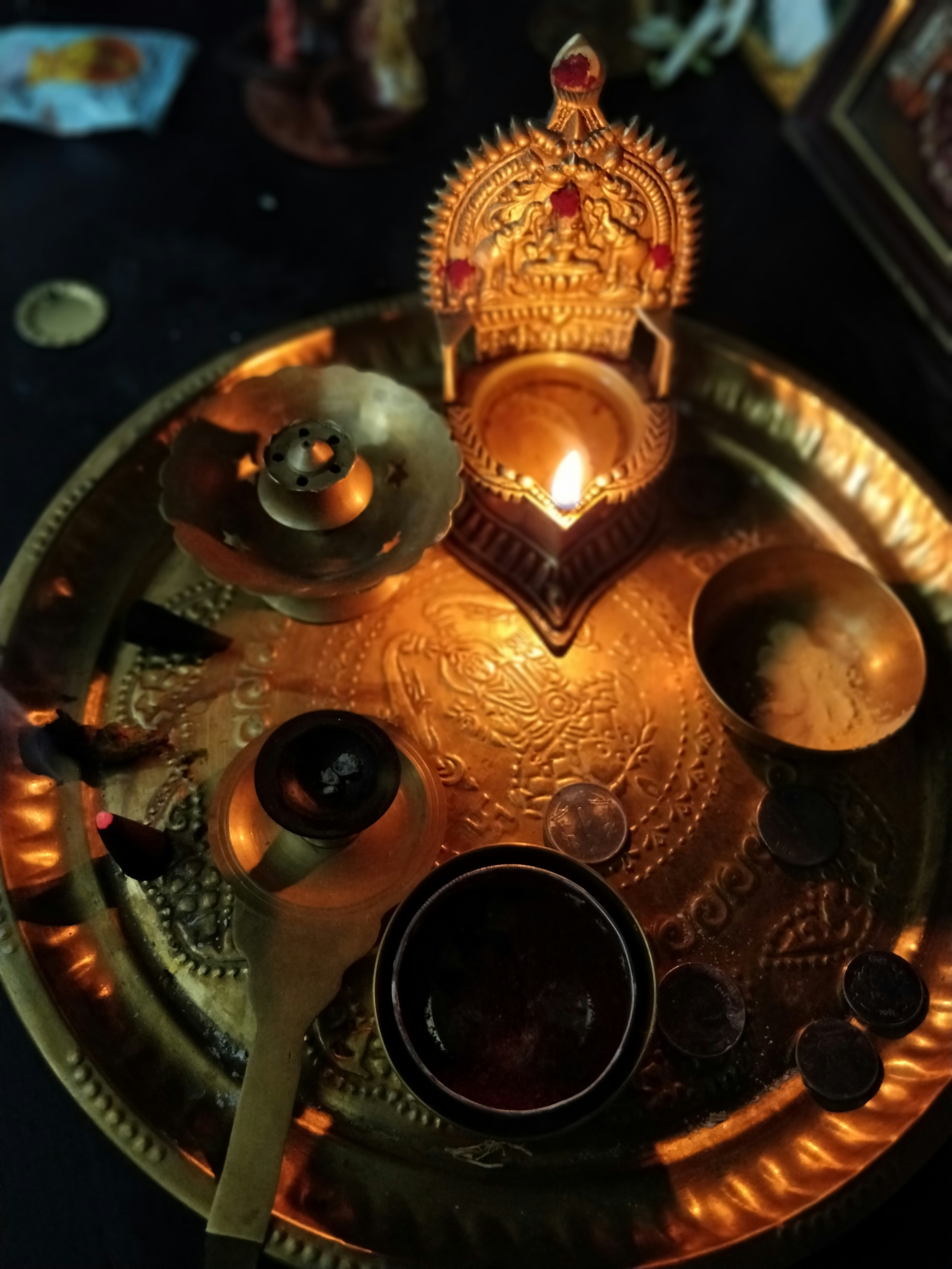Elaborate puja thali with marigolds, kumkum, and brass lamp, warm golden candlelight, richly decorated altar, deep amber tones, ceremonial setting
