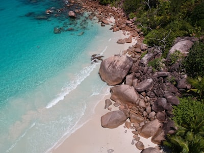 brown rocks near body of water seychelles teams background