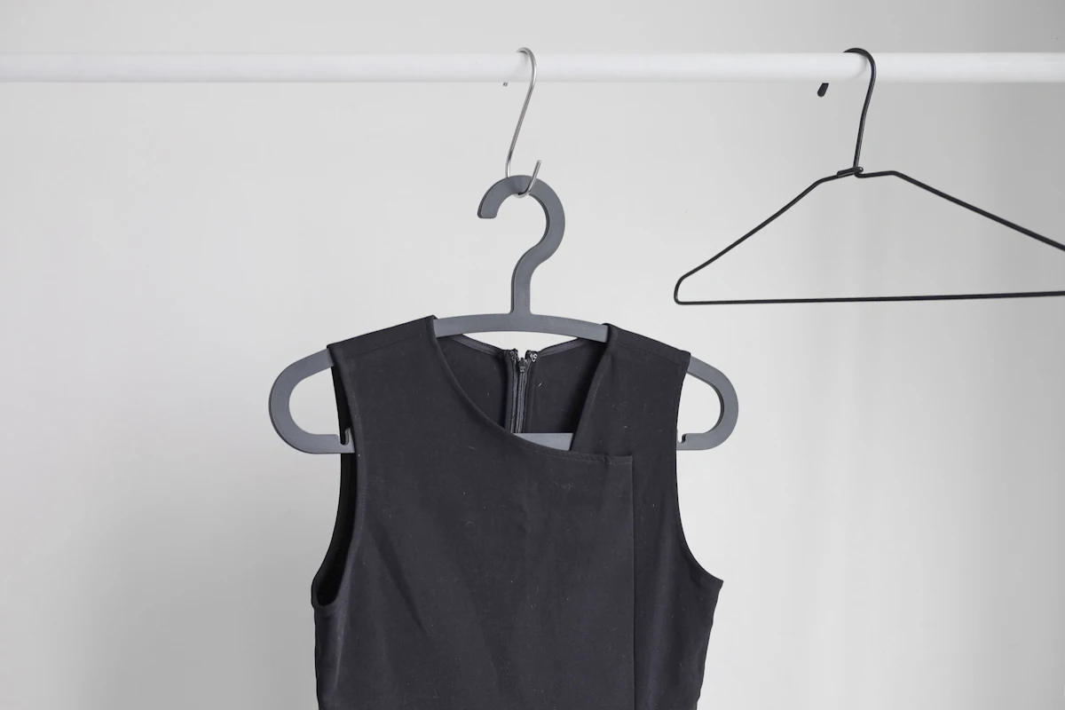 Kaus jersey gelap tanpa lengan menggantung di hanger, memperlihatkan lubang lengan dalam khas jersey basket