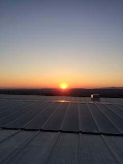 Sunset view of a home with a sleek metal roof reflecting warm orange hues