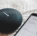 turned-on charcoal Google Home Mini and smartphone