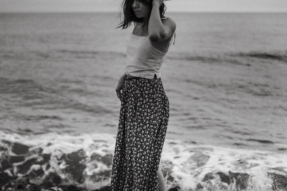 grayscale photography of woman standing on shore