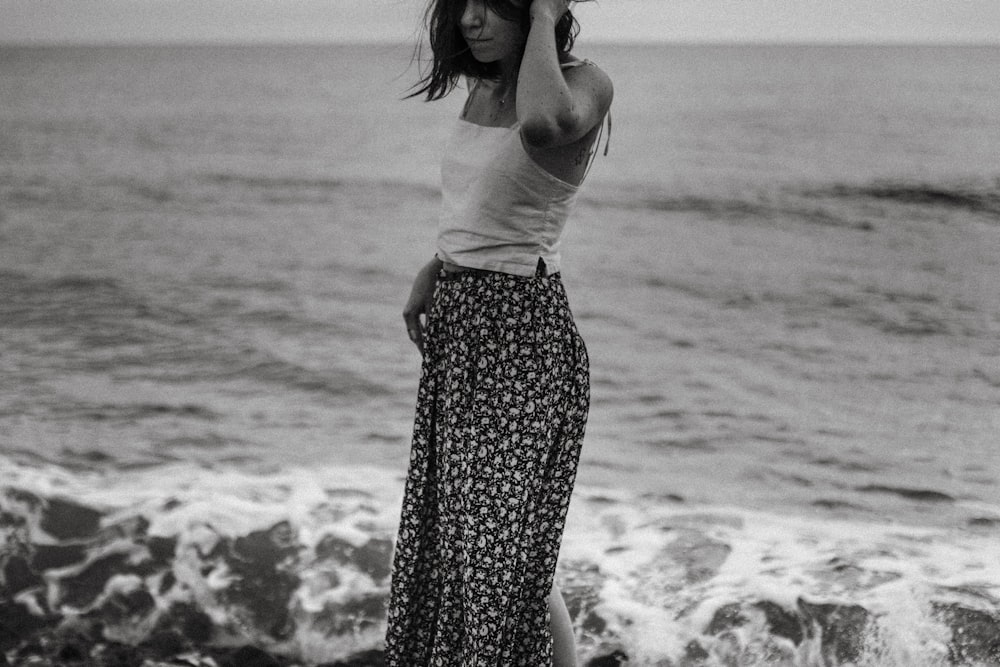 Photographie en niveaux de gris d’une femme debout sur le rivage