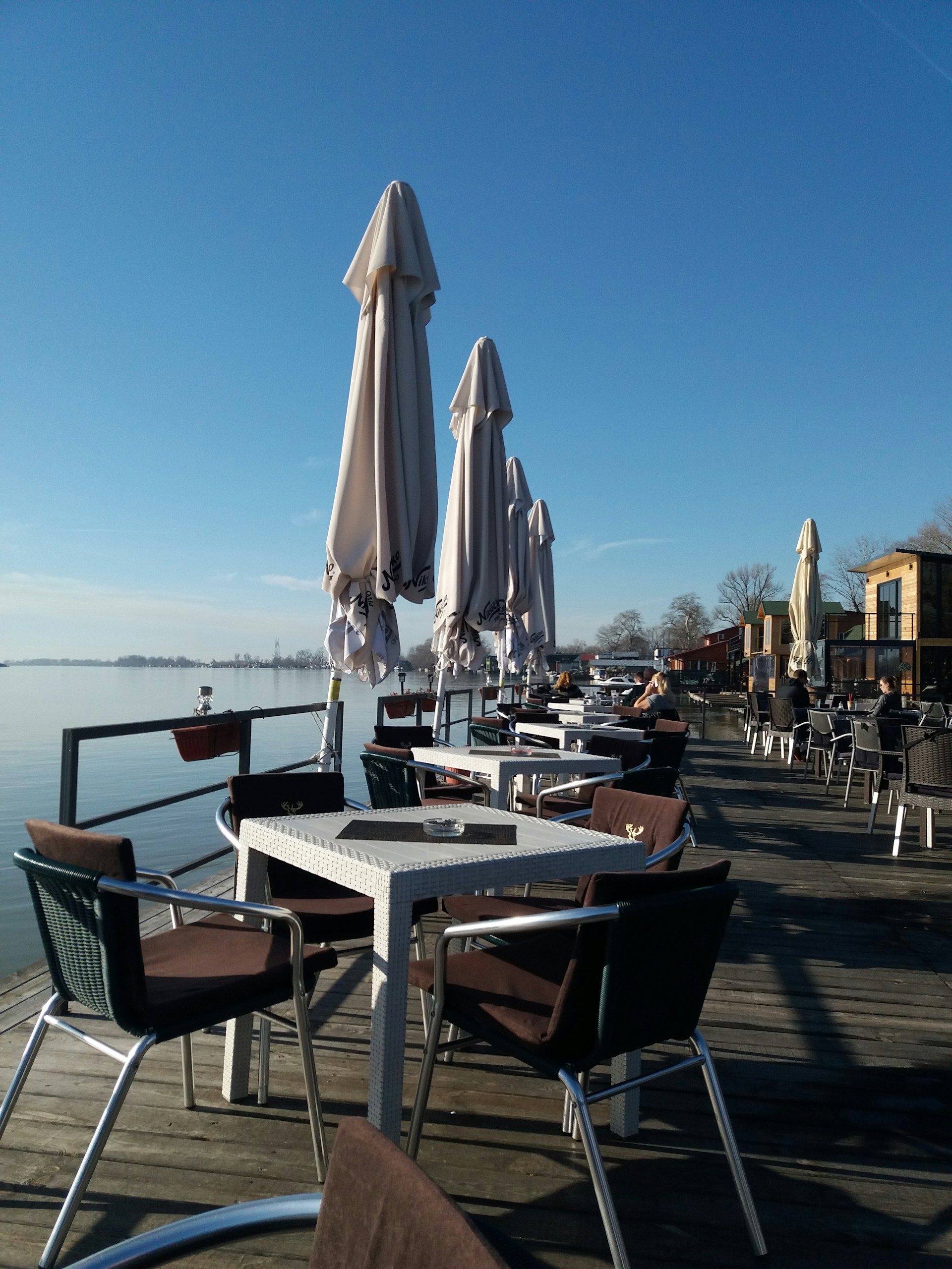 An inviting outdoor dining area with wooden tables overlooking the water, perfect for enjoying meals in nature.