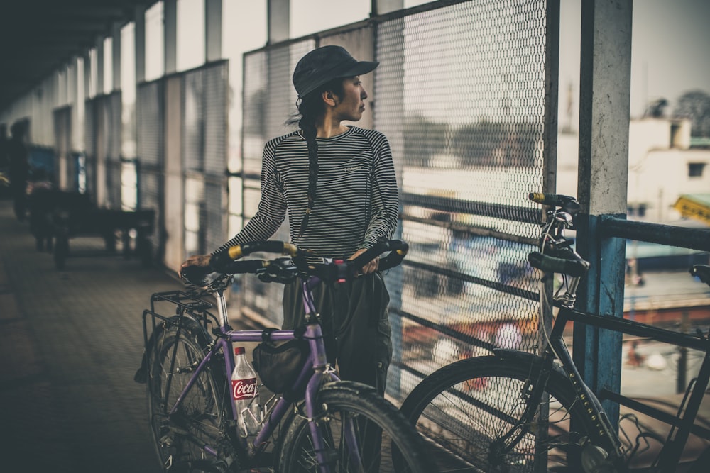 Donna che tiene la bicicletta viola della città