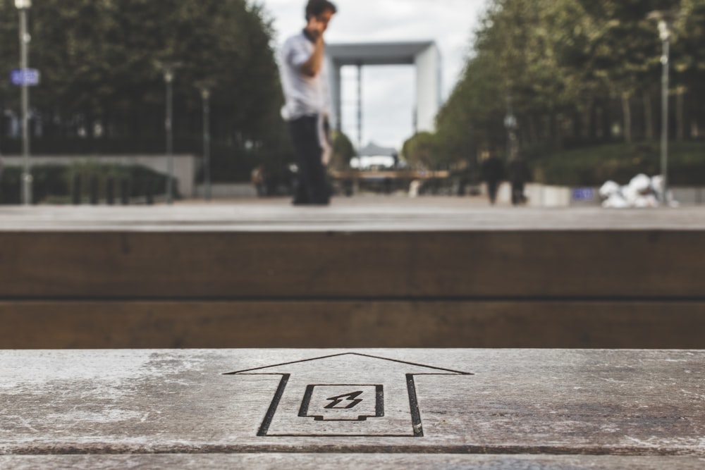 arrow sign heading to man using smartphone during daytime