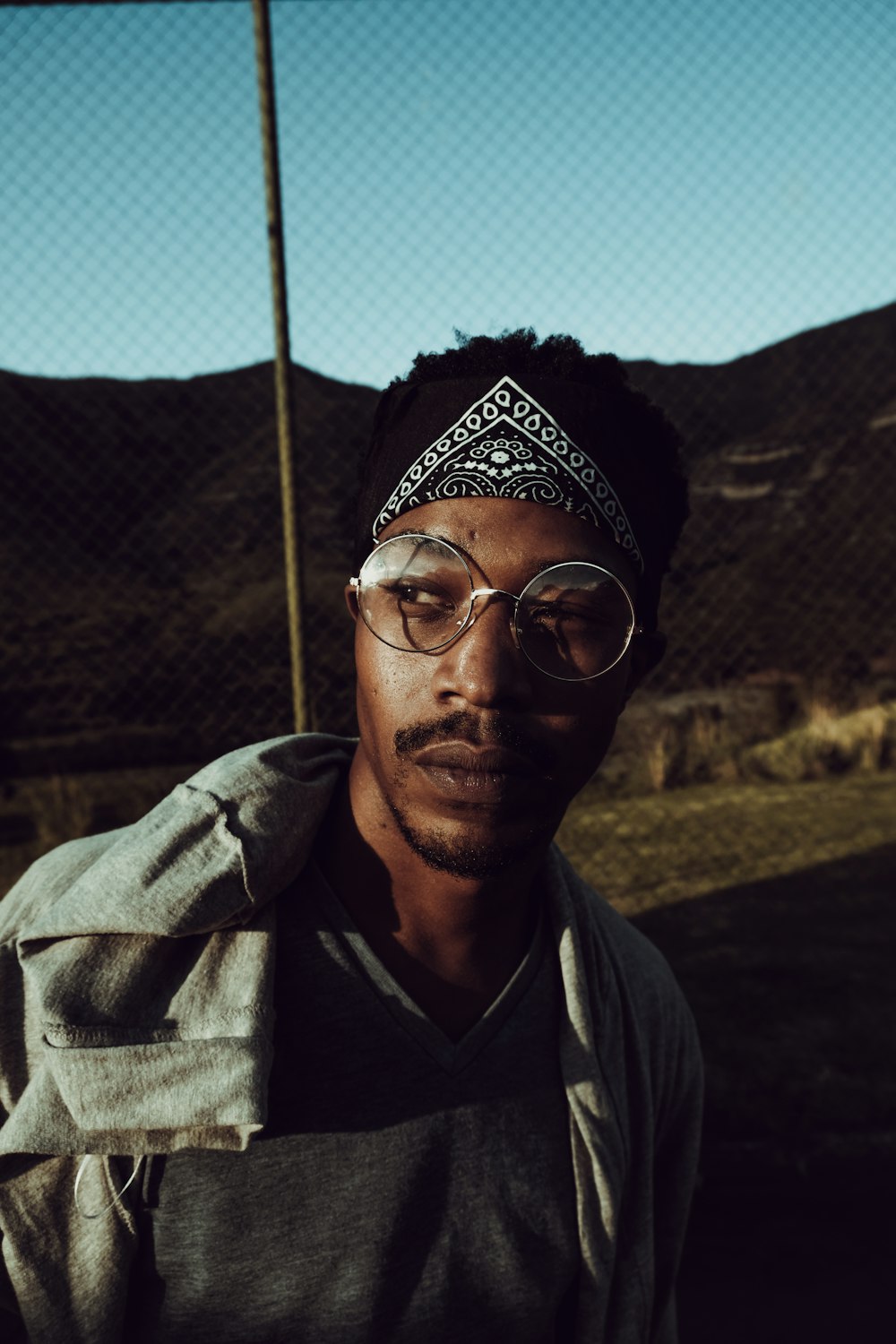 man posing for photo near chain link fence during daytime