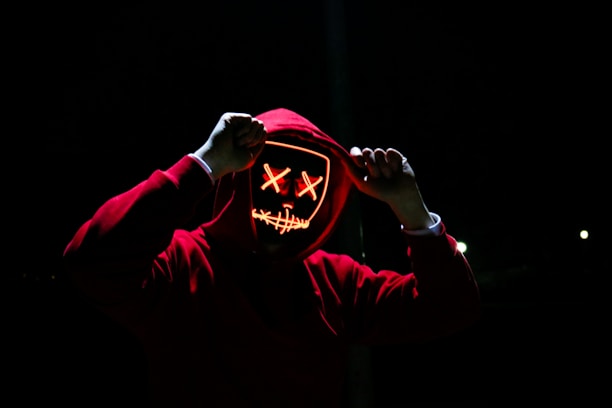 Close-up of a black hoodie with red neon accents in an urban alley setting.