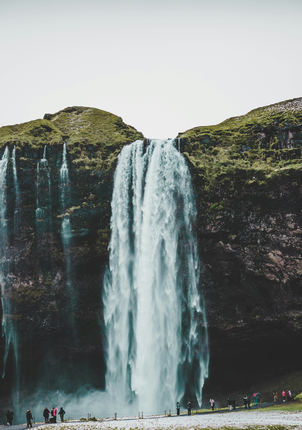 group of people standing near waterfalls