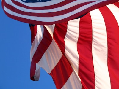 An artistic shot of a red fabric flowing in the wind against a clear sky.
