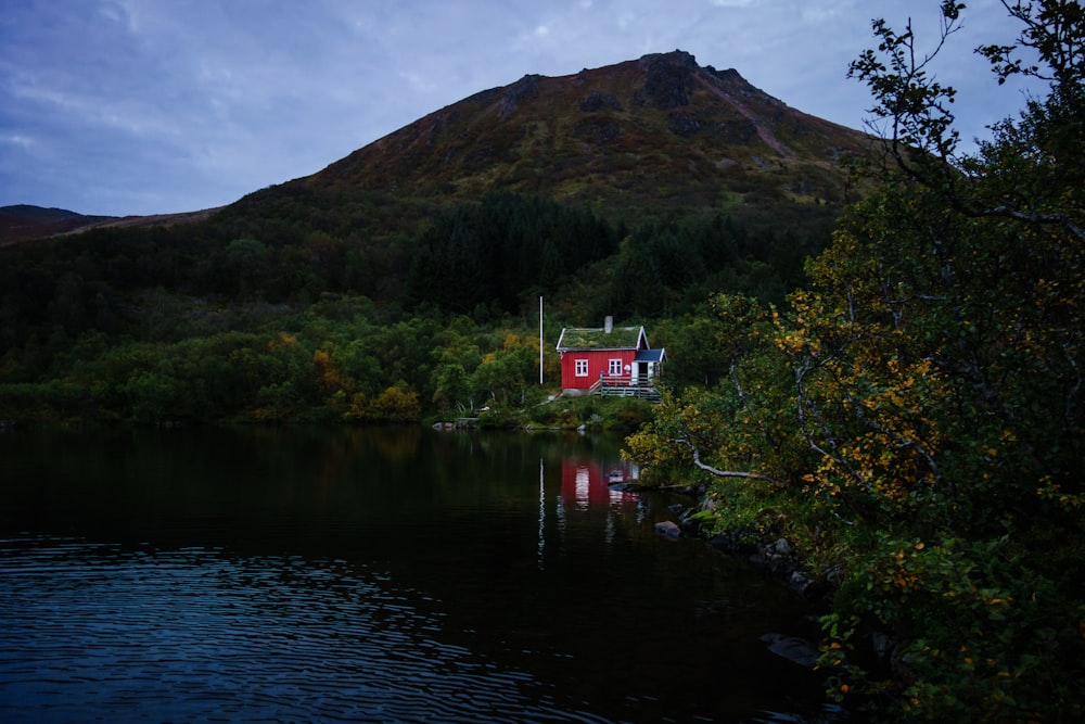 a red house sitting on top of a lush green hillside