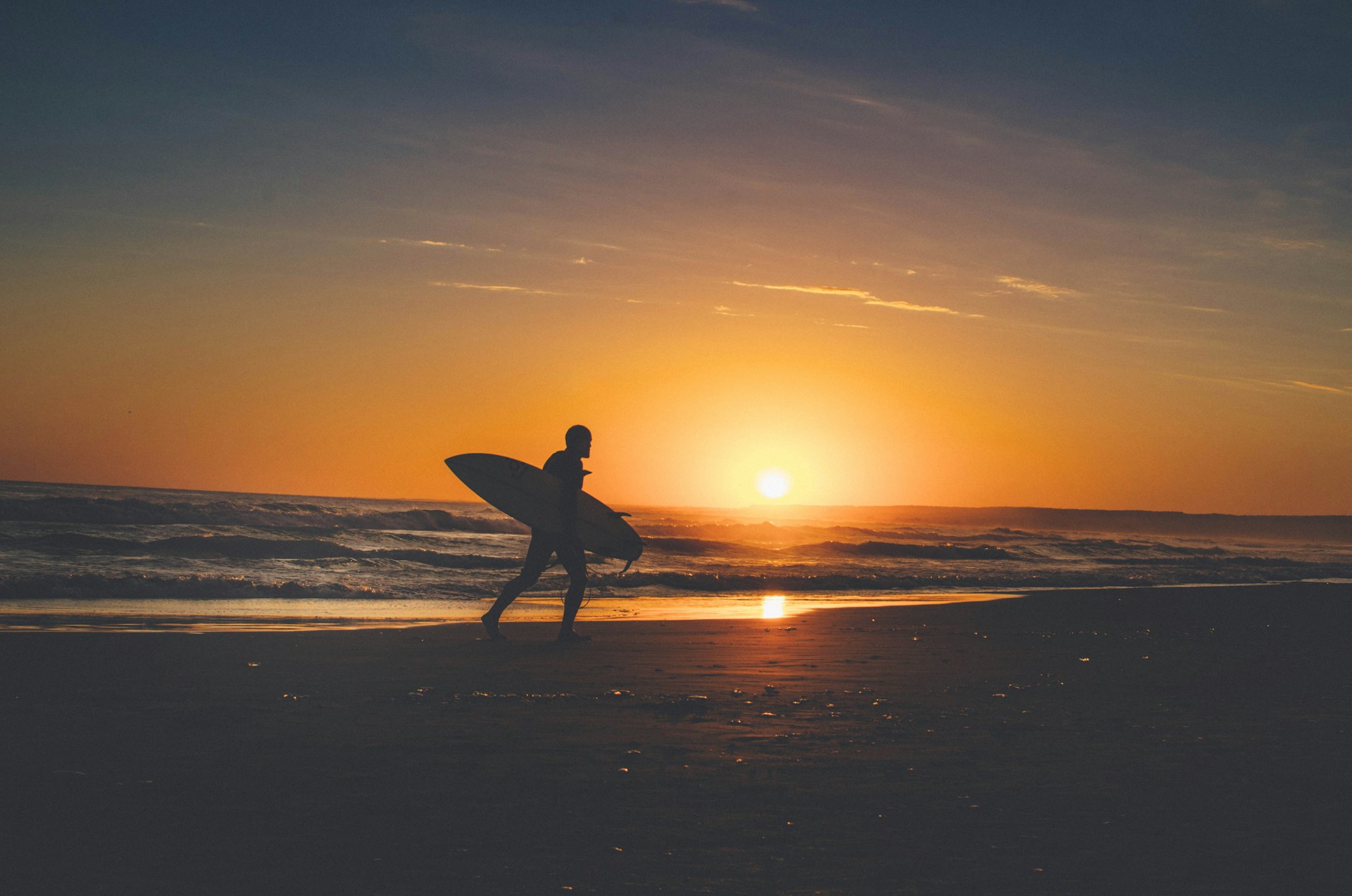 silhouette of person holding surfboard near body of water