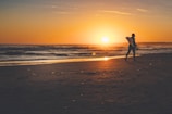 A happy surfer holding a freshly repaired surfboard on the beach at sunset