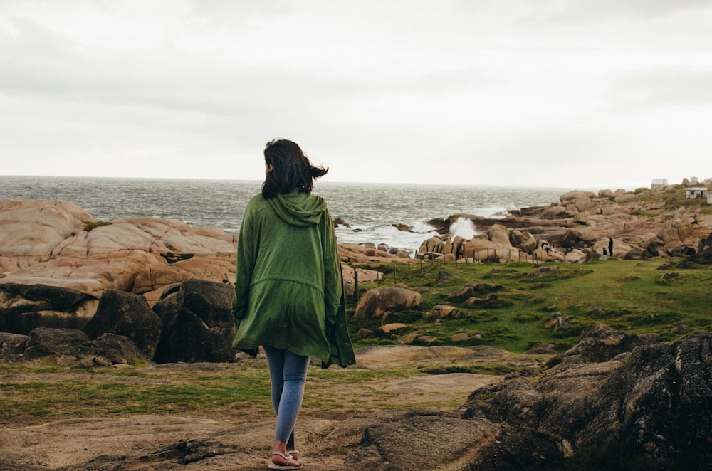 femme marchant près d’un rivage rocheux