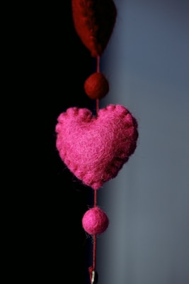 Pink felted heart hanging on a wall hook