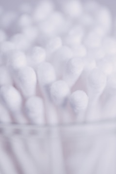 A close-up view of several white cotton swabs, with soft, fluffy tips. They are closely packed together, creating an abstract, textured appearance.