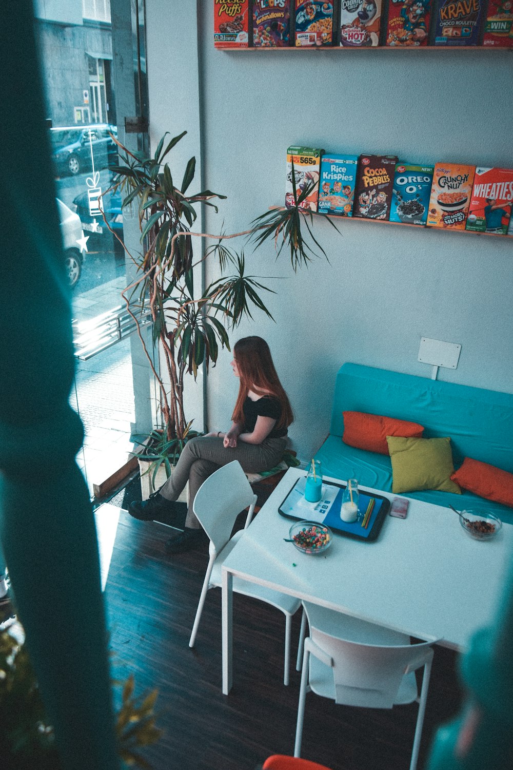 woman sitting near table under shelves with boxes