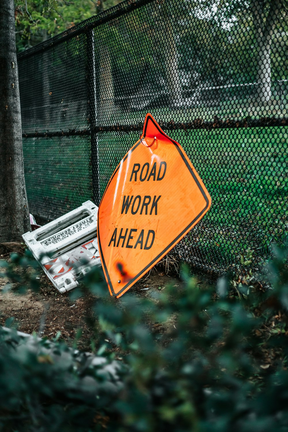 Signalisation des travaux routiers à venir appuyée sur une clôture à mailles losangées