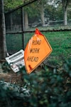 road work ahead signage leaning on chain link fence